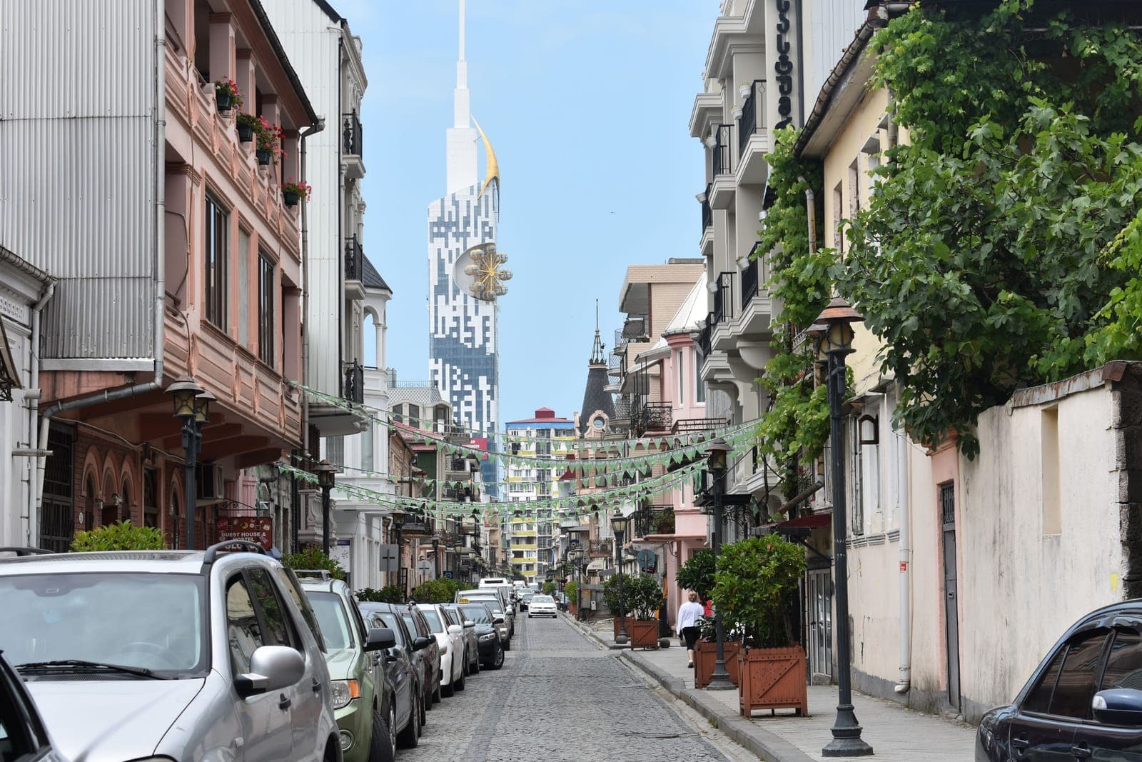 巴统一条狭窄街道旁停满汽车，身后高耸着巴统塔