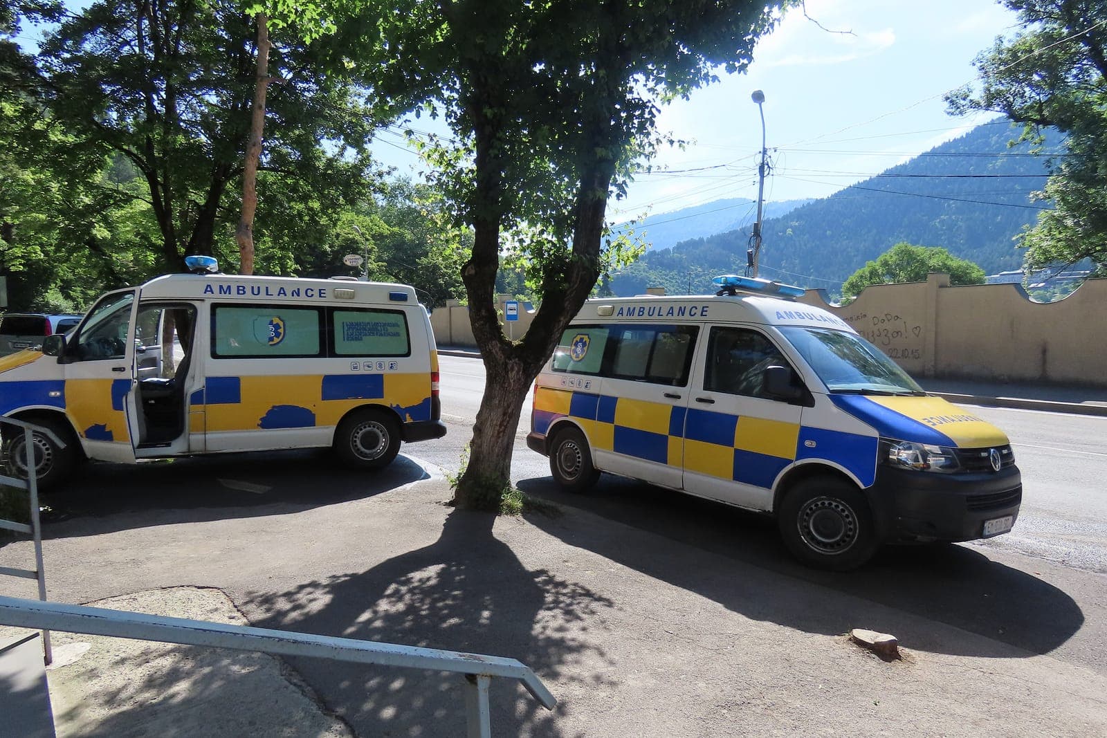格鲁吉亚博尔若米街边停着两辆救护车,身后是林木茂密的群山