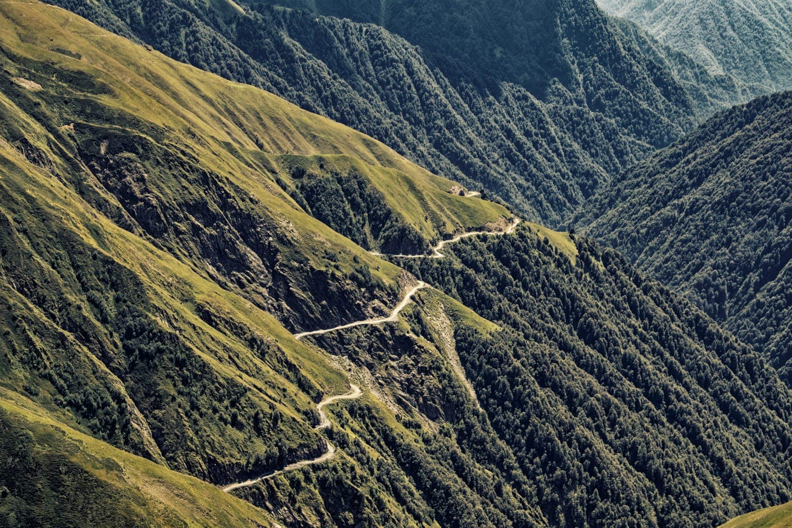 图舍蒂阿巴诺山口公路的砂石发夹弯,沿陡峭的绿色山坡盘旋而上