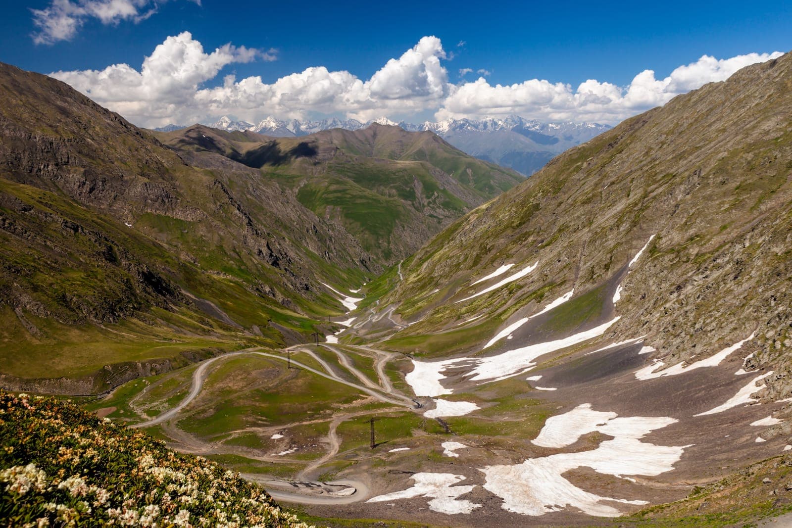 图舍蒂阿巴诺山口公路的砂石之字弯道,穿过残雪斑驳的高山谷地蜿蜒而下
